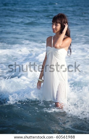 Beautiful brunette model standing in water in wet white dress. Southern Tenerife, Canary Islands.