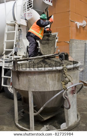 Truck operator pouring cement into crane bucket