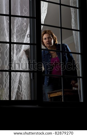 Woman looking out from behind a window