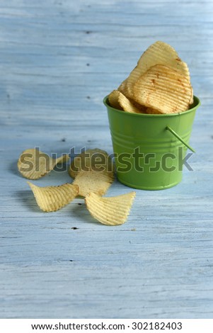 Potato chips in a bucket on old wooden table