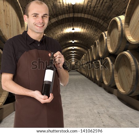 Young man presenting a wine bottle in the cellar