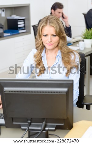 Woman working at her desk, with people working at the background