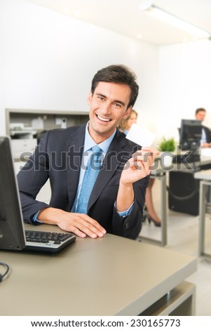 Man at his office desk holding a business card