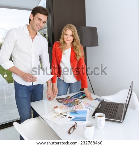 Man and woman in an office surrounded by color charts, material samples and technology