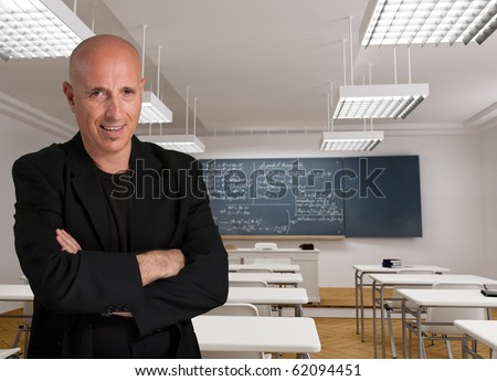 Bald man in a black suit in a classroom with mathematic formulae