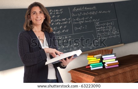 Cheerful female teacher holding a book in a maths classroom