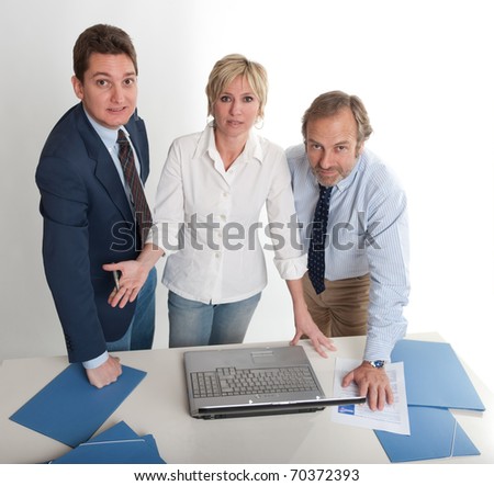 Three people around a laptop looking at the camera