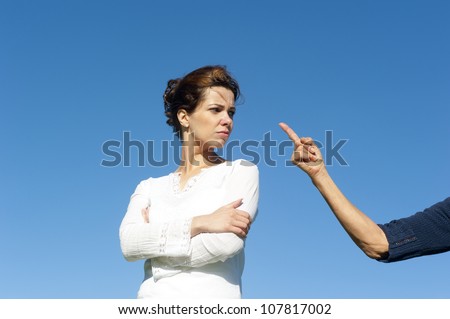 Two  generations, mother and daughter argueing, fighting, communicating. With one arm and finger pointing towards young girl. Isolated with blue sky as background and copy space.