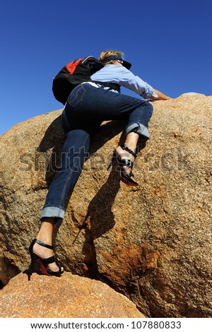 Mature woman in jeans and high heel shoes walking, traveling, hiking through Devils Marbles in Australian outback.