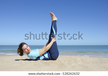 Sexy fit and healthy young woman doing gymnastic or yoga exercising at tropical beach, isolated with ocean and blue sky as background and copy space.