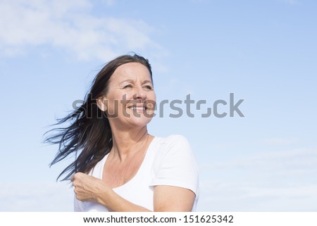 Portrait attractive mature woman joyful and happy retired, keeping healthy and fit, isolated on blue sky background and with copy space.