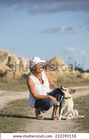 Portrait of attractive mature woman with her pet friend at sunny day outdoor, happy, smiling, having fun, while dog is showing love and affection.