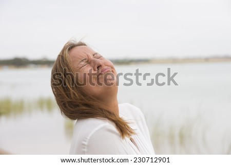 Portrait depressed mature woman with sad, stressed, painful facial expression, crying with closed eyes outdoor, blurred background and copy space.