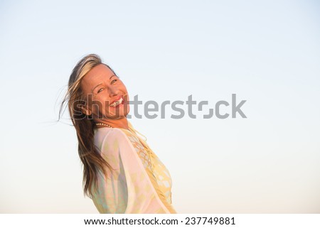 Portrait beautiful brunette mature woman smiling happy relaxed and joyful, confident and laid back, with clear sky as outdoor background and copy space.