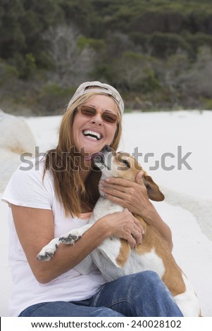 Portrait happy smiling attractive mature woman showing love and affection with licking pet dog outdoor, blurred background.