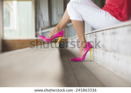 Concept close up image of woman sitting in Elegant sexy pink high heel shoes, sitting relaxed on bench, copy space, blurred background