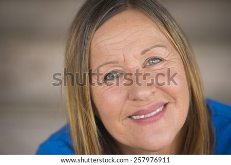 Portrait attractive mature woman with happy relaxed confident facial expression, smiling friendly, blurred background.