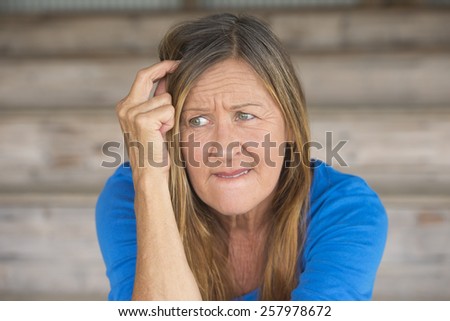 Portrait attractive mature woman with upset thoughtful angry facial expression, lonely worried, blurred background.