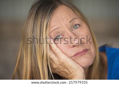 Portrait attractive mature woman with bored, stressed, lonely, depressed and sad facial expression, blurred background.