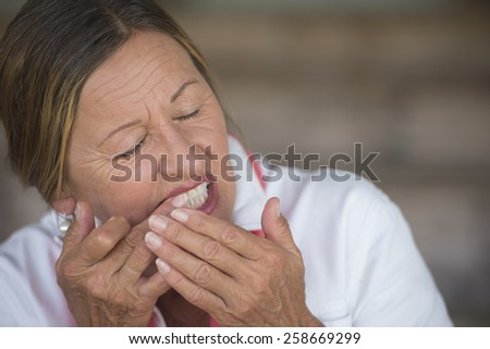 Portrait attractive mature woman in pain with toothache, stressed and unhappy facial expression, closed eyes, blurred background, copy space.