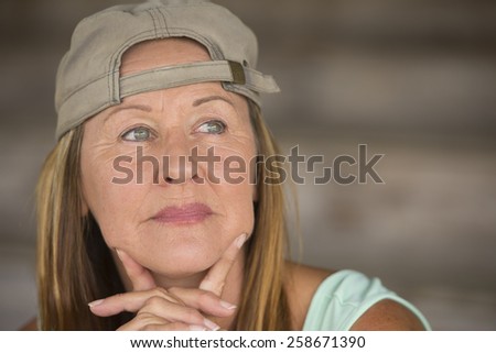 Portrait attractive fit active mature woman wearing green sporty top and cap, thoughtful relaxed confident, chin resting on hands, blurred background, copy space.