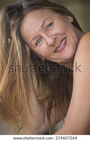 Portrait attractive mature woman smiling confident relaxed with hand seductive in long brunette hair, blurred background.