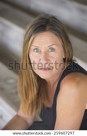 Portrait attractive mature woman sitting alone and lonely, sad thoughtful facial expression, upward look, blurred background.