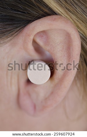Detail image of female ear blocked with protective ear plug.