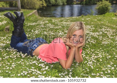 Young woman outside in the park laying on the green grass