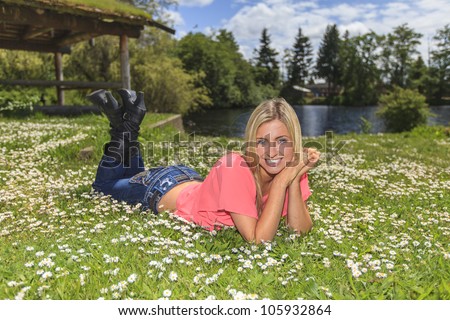Young woman outside in the park laying with pink shirt and jeans