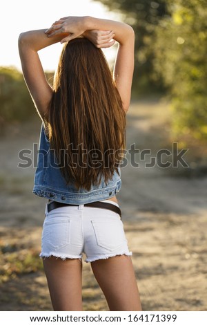 Women posing from behind in a white jeans shorts and jean jacket