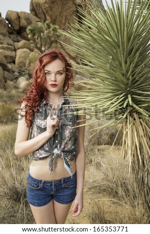 Young happy model posing at Joshua Tree desert and enjoying the environment and wearing jeans shorts