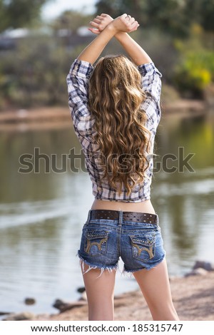 Beautiful model posing with long hair and flannel shirt and jeans shorts