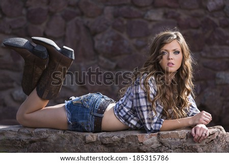 Young lady with flannel shirt and boots laying on the ground