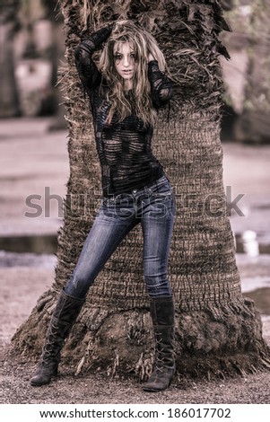 Crazy and scary young woman posing in jeans and large boots with tight black shirt