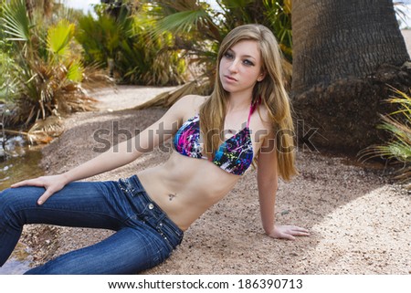 Young blonde girl posing and laying on a warm beach