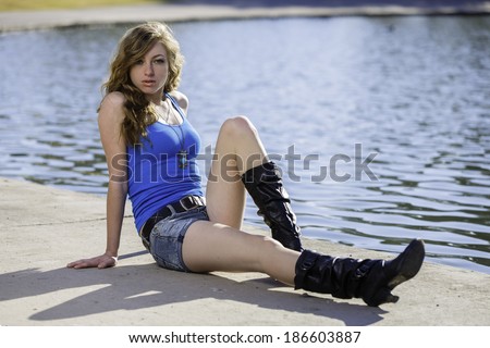 Young blond model laying on the ground and posing in large black boots