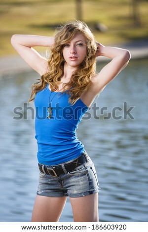 Young model posing by a lake wearing blue summer wear colors