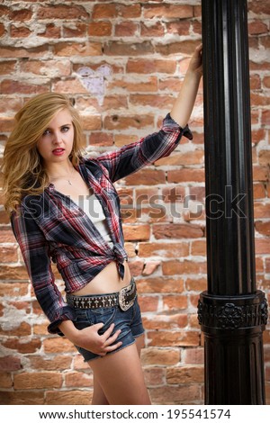 Beautiful young girl in flannel shirt and low rise jeans shorts