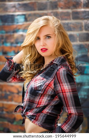 Portrait of a blond girl in flannel shirt and posing