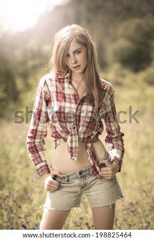 Southern country American girl posing in denim shorts and red flannel shirt