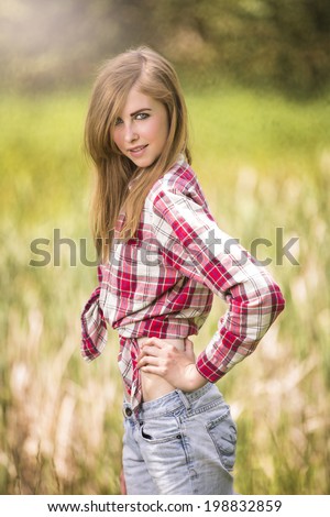 Happy young country western girl posing in red flannel tied shirt and jeans
