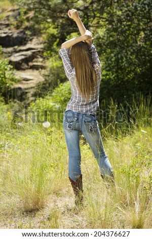 Brunette model posing in flannel shirt and jeans pants from behind