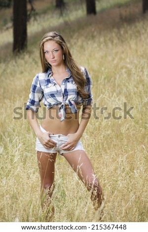 Gorgeous young girl in blue flannel shirt and white pants posing in western wear