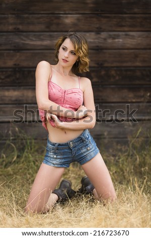Young female model posing with both hand together and wearing pink top and denim jeans shorts