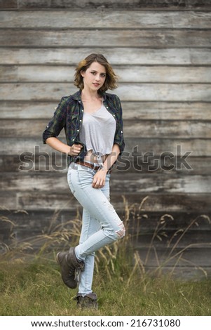 Short hair female girl wearing dark color flannel shirt posing with one leg up