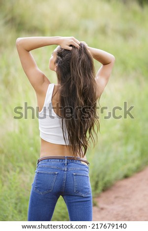 Stunning young model with dark brown long straight hair posing from behind