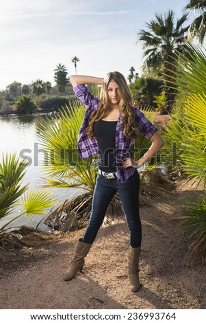 Sassy young model wearing purple flannel shirt posing by a tropical lake