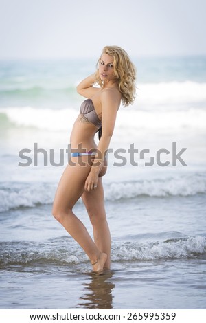 Slim and young blonde girl posing in the water in a bike swimwear