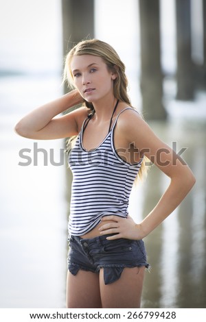 Attractive young portrait woman posing in cut off shorts with one arm on her head